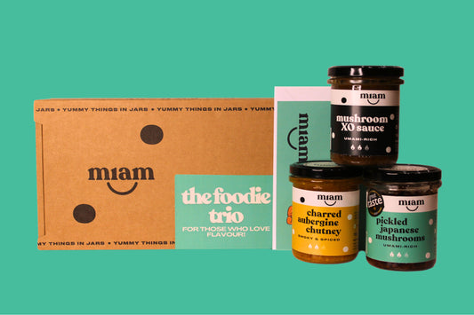 Collection of miam food products including jars and a box on a teal background